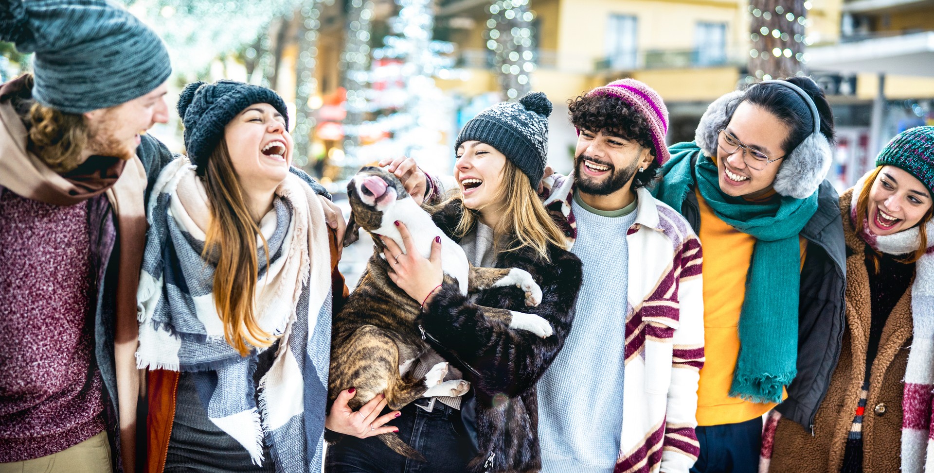 Happy friends group having fun together with cute dog on winter holidays - traveling with service dog